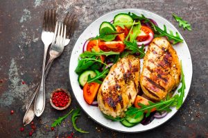 Nutritious meal with grilled chicken, tomatoes, and green salad