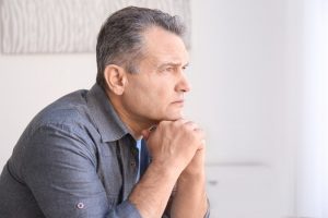 Older man sitting with hands under chin