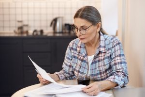 Middle-aged woman sitting at table looking at documents