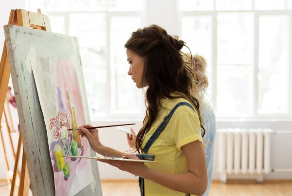 Woman standing at easel, painting on canvas