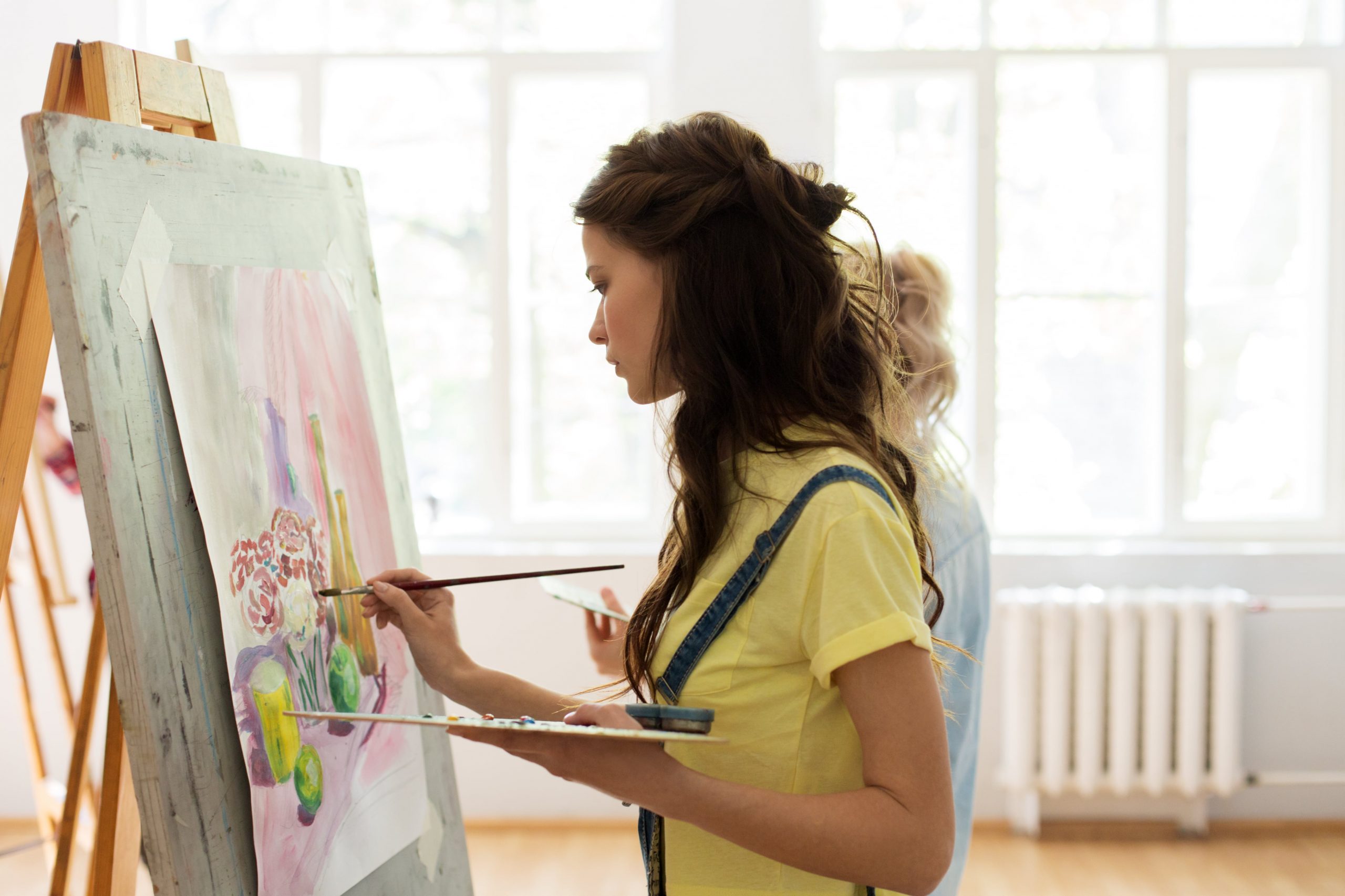Woman standing at easel, painting on canvas