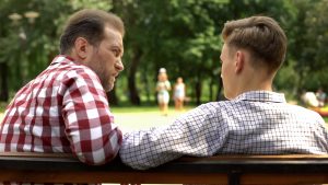 Father and son sitting on bench talking