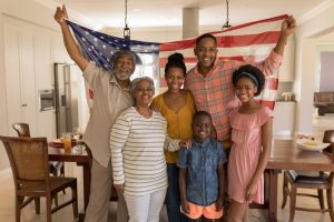 Family of 6 standing in living room, draping American flag on their shoulders