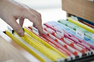 hand searching through filing cabinet drawer