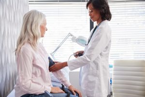 Woman visiting her doctor, getting blood pressure taken