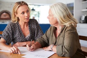 Adult daughter and mother looking at documents while sitting at table