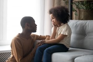 Dad talking kindly to sad young daughter