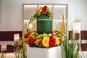 Green urn sitting in a prominent location, surrounded by yellow and red flowers