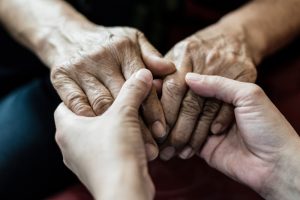 Younger person holding older person's hands, focus on hands only