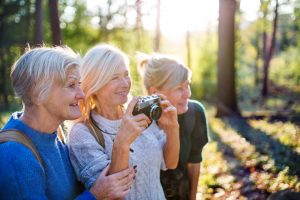 Three women in the woods, taking photographs of nature, supporting each other through friendship