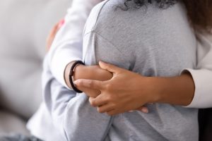 One person hugging a loved one, focus on shoulder and hands