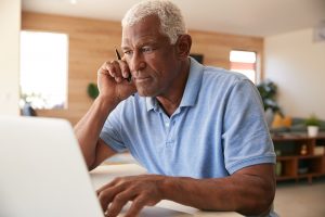 Older man on the phone while looking at computer