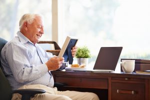 Man sitting at desk in his home, holding a photo frame and smiling at the image