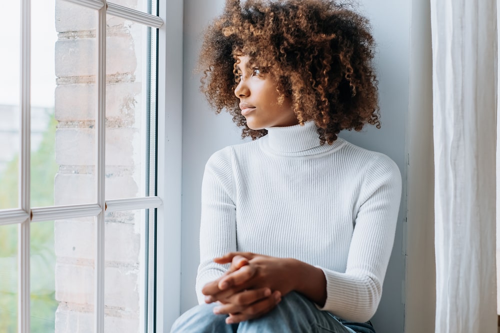 Young woman in white sweater looking out the window