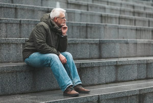 Older man sitting quietly on stone steps as he thinks