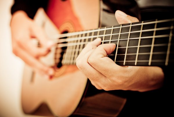 Man playing guitar, focus on strings and hands