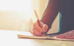 Man siting at desk, writing in journal, expressing himself