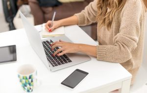 Young woman sitting at desk, typing on her computer