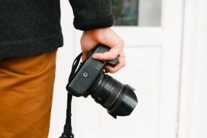 Man holding camera in right hand, held by his thigh