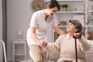 Hospice nurse helping older woman stand