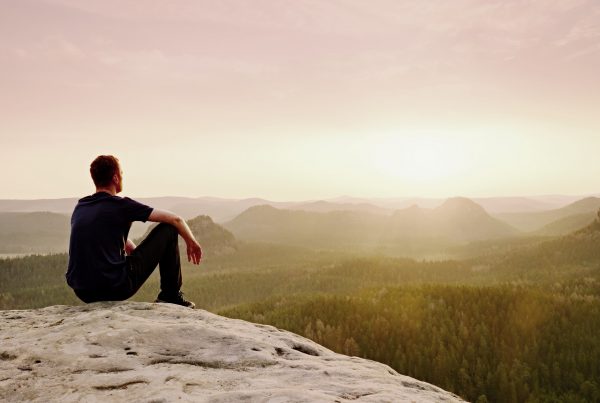 Man sitting on rock outcropping, resting and recharging in nature