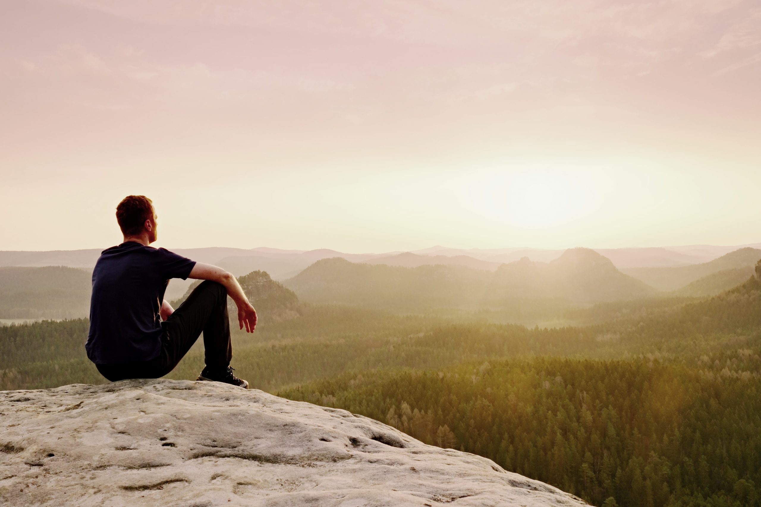 Man sitting on rock outcropping, resting and recharging in nature