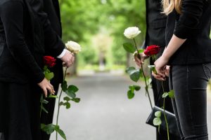 Parents and two teenagers wearing black and carrying funeral roses