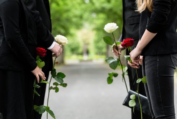 Parents and two teenagers wearing black and carrying funeral roses
