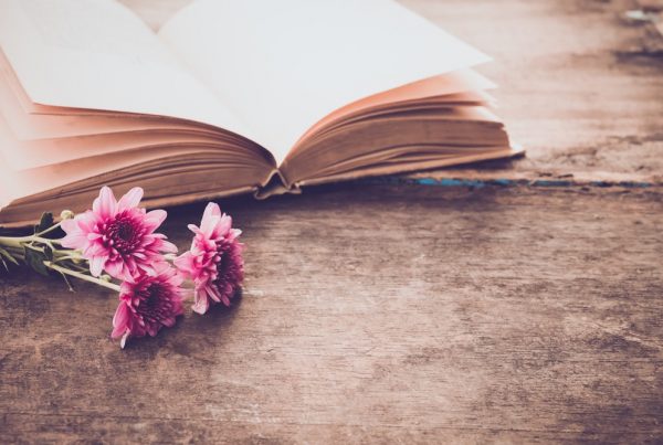 open book with pink flowers next to it