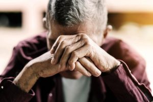 Sad middle-aged man resting head on hands