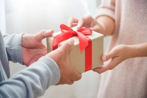 One person giving a gift-wrapped box to another person