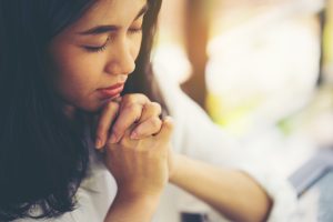 Teenage girl praying, hands clasped