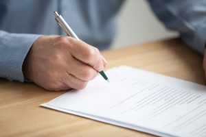 Man looking at document, pen poised to sign the bottom