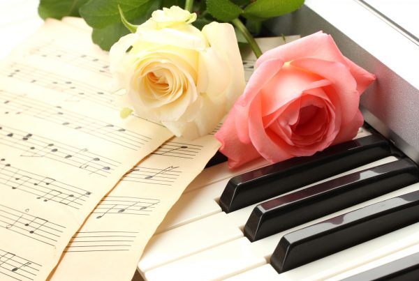 Two roses and music sheets laying on piano keys