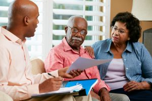 Older couple sitting at home with funeral director, looking at documents, options, and pricing