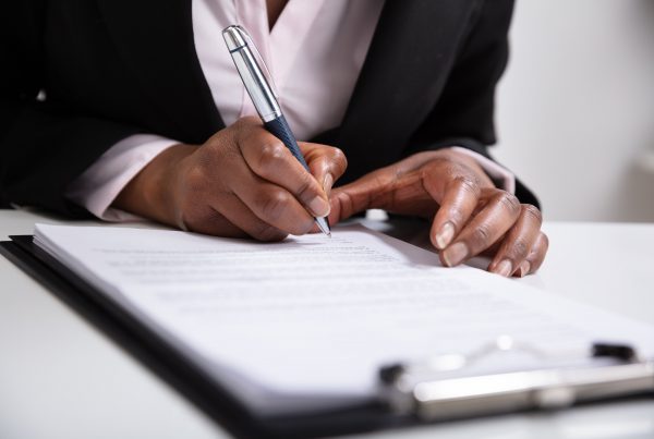 Focus on woman's hands as she signs documents on a clipboard