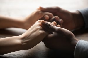 Two people holding hands, offering comfort