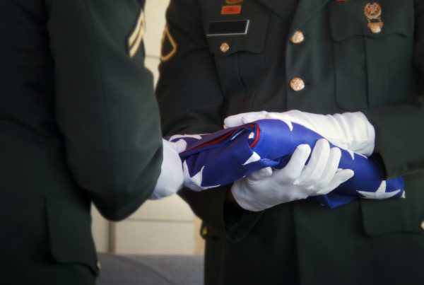 Two men in uniform folding the American flag