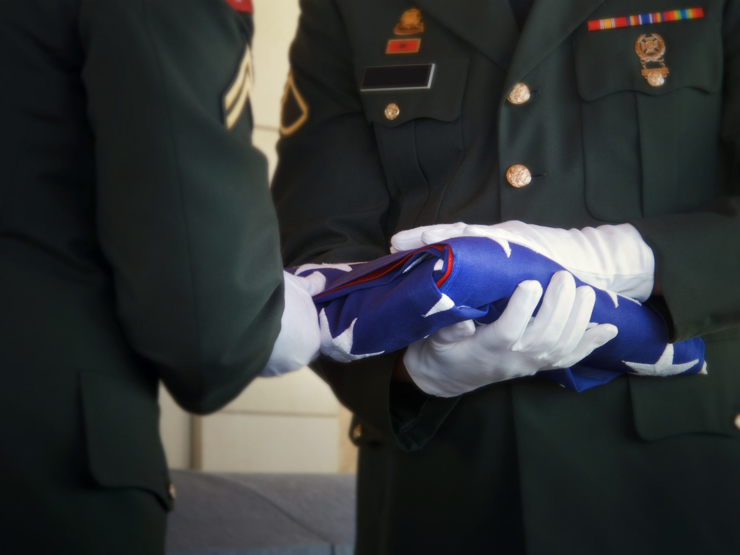 Two men in uniform folding the American flag