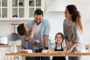 Young blended family of 4 having fun baking in the kitchen
