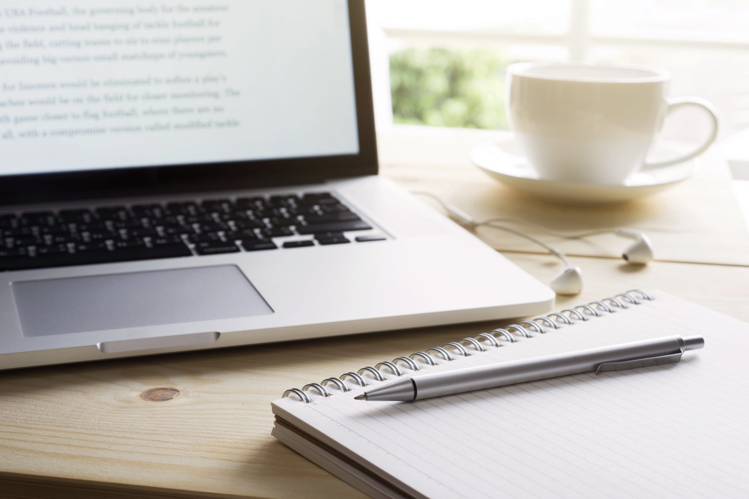 Open laptop sitting on desk with notepad and pen nearby