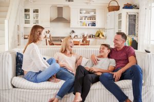 Blended family sitting on couch, enjoying each other's company, mom, dad, teenage son, and teenage daughter present