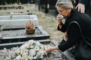 Grieving woman laying flowers on a loved one's grave