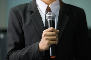 Man in dark suit speaking into microphone