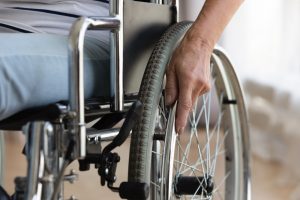 Close-up of wheelchair, person sitting in chair but you can only see part of leg and hand