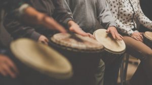 line of people playing on bongo drums
