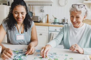Young female volunteer and older woman working on a puzzle together
