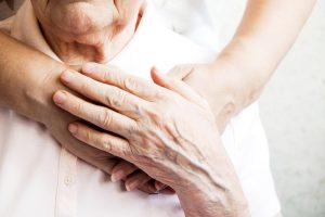 Young person places comforting hands on elderly person's heart