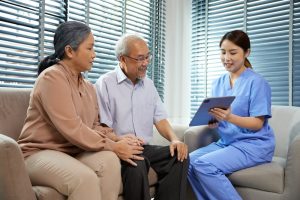 A healthcare worker speaking to two older adults.